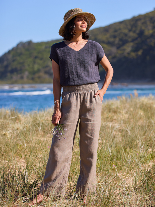 Woman standing in a grassy field with mountains and water in the background