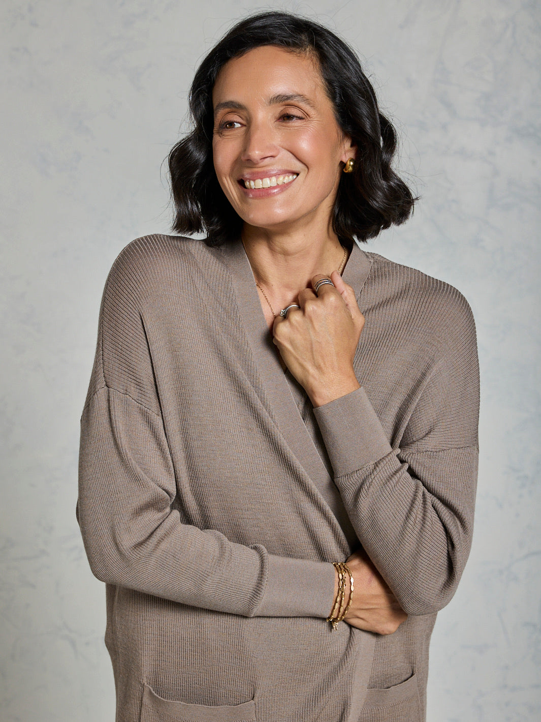 Woman wearing a brown sweater against a plain background
