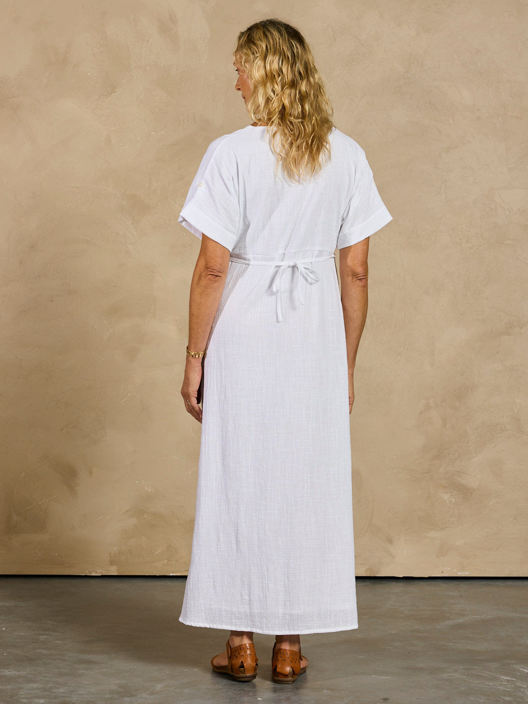 Woman wearing a white dress against a beige wall