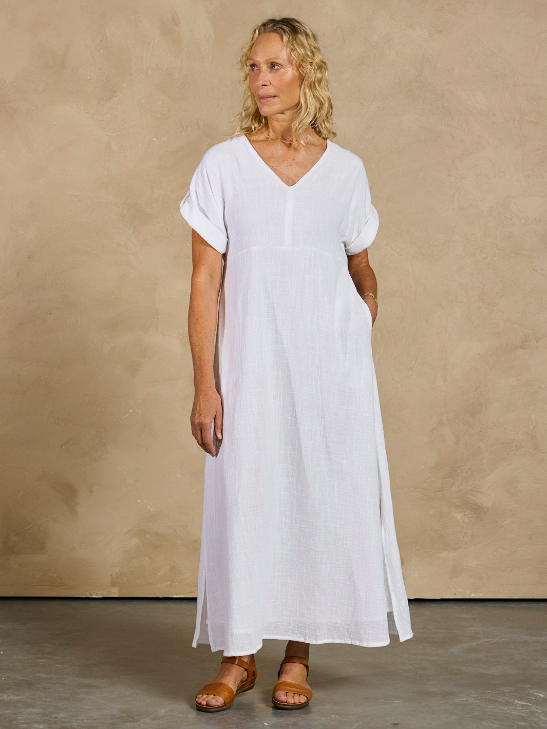 Woman wearing a white dress against a beige background