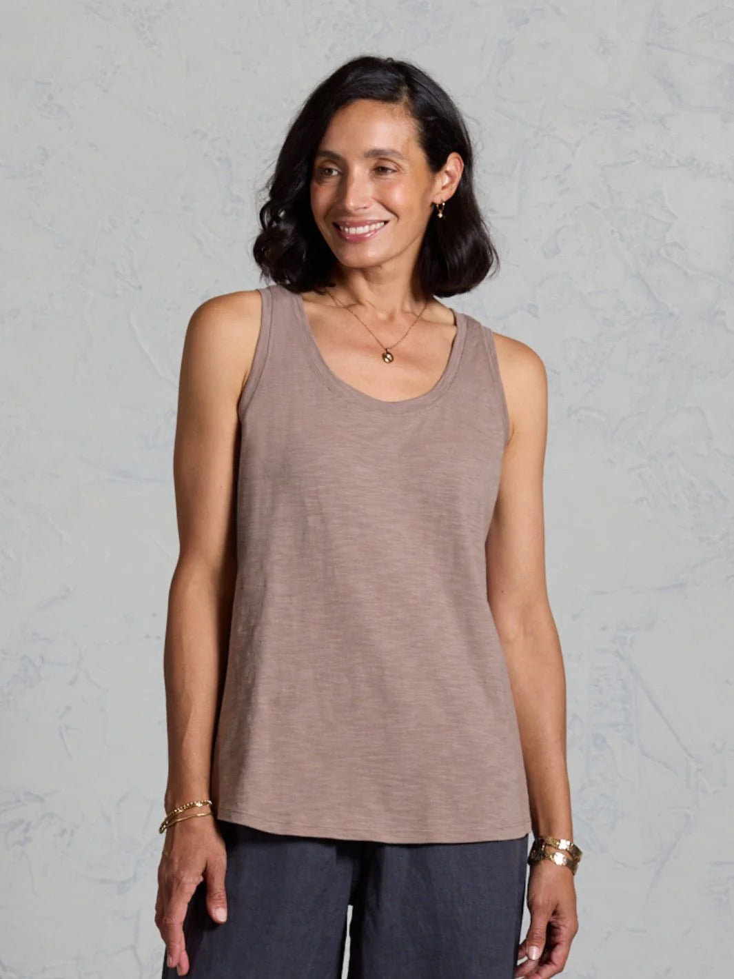 Woman wearing a brown tank top against a gray background