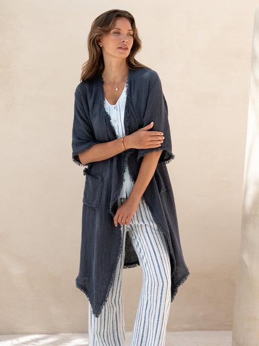 Model wearing the Laguna French Linen Kimono in charcoal, layered over a blue top and striped linen pants