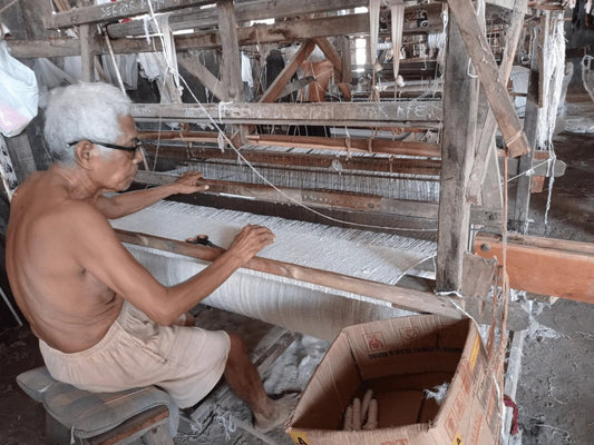 a man is weaving fabrics with a wooden loom