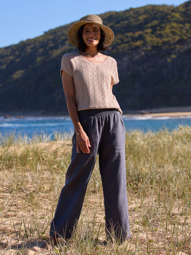 Woman standing in a natural setting with mountains and water in the background