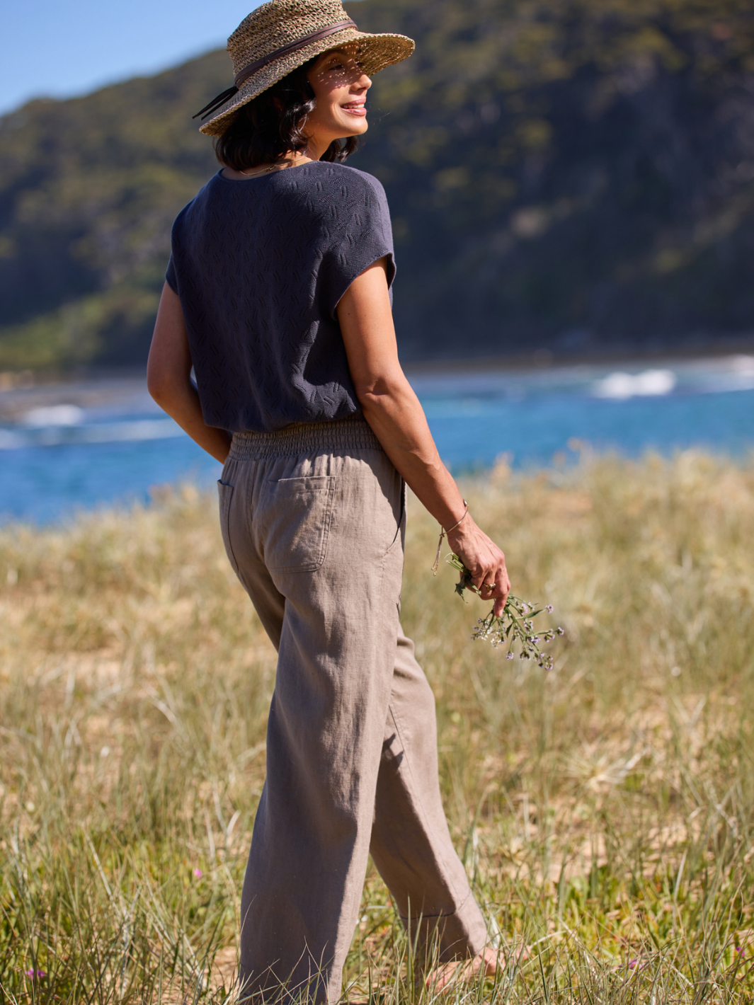 Woman walking on a grassy field by the ocean.