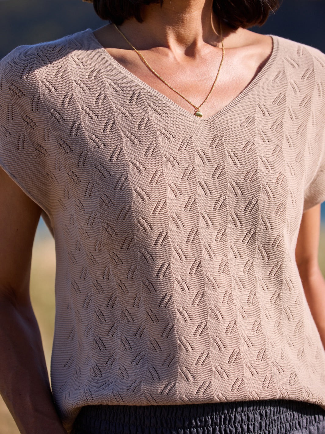 Person wearing a light textured knit top with a blurred background