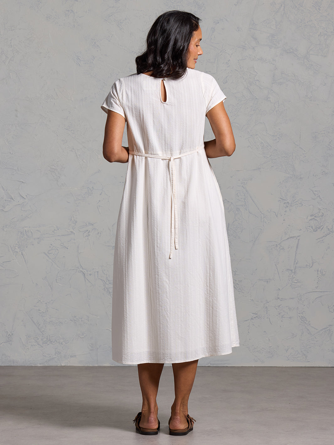 A woman wearing a cotton dress in coconut from Nomad the Label