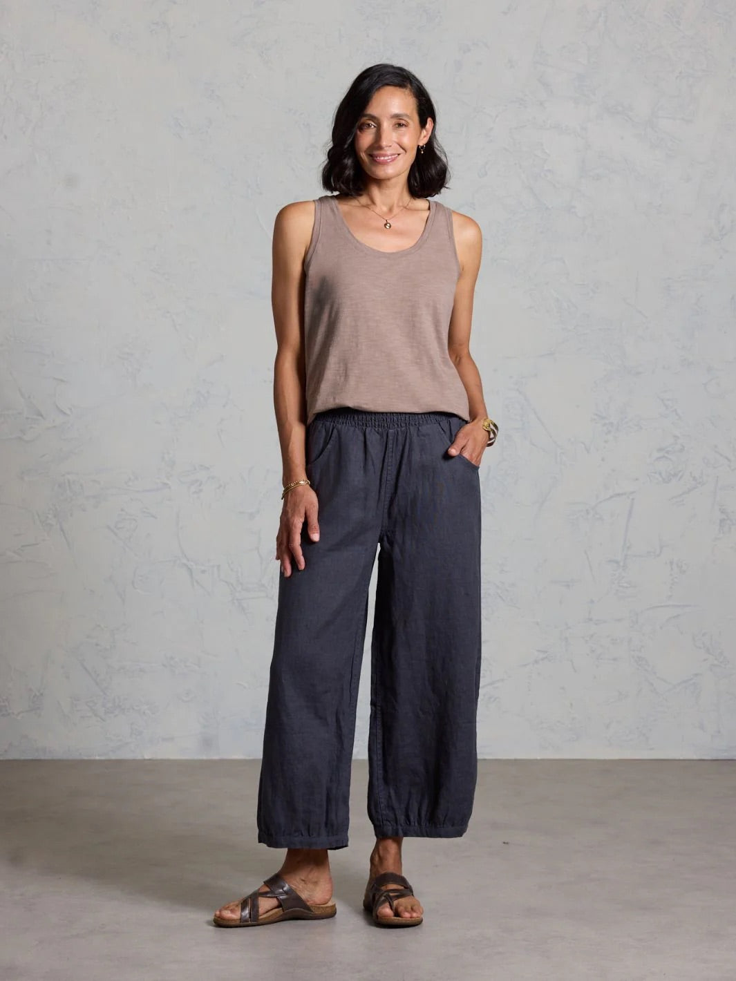 Woman wearing a sleeveless top and wide-leg pants against a plain background