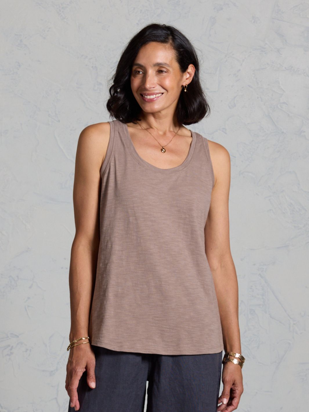 Woman wearing a brown tank top against a gray background