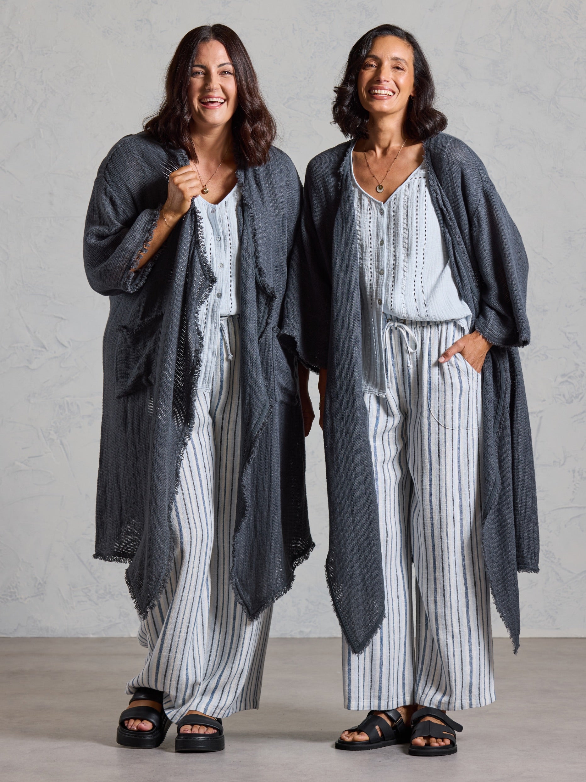 Two models wearing the Laguna French Linen Kimono in charcoal with blue tops and striped linen pants